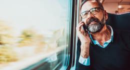 Homme au téléphone assis à coté d'une fenêtre dans un train